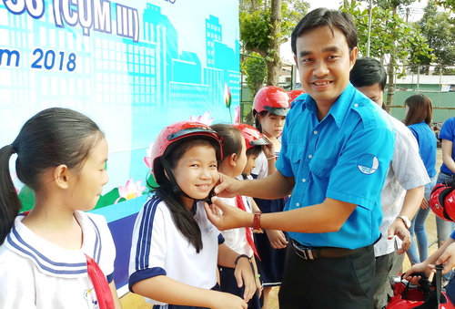 anh Nguyễn Văn Vũ Minh - chủ tịch Hội LHTN Việt Nam tỉnh Đồng Tháp tặng mũ bảo hiểm cho học sinh